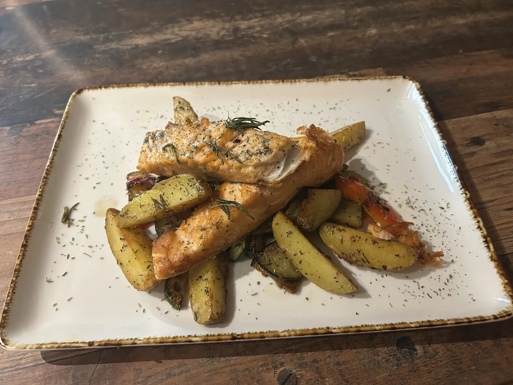 Gebratenes Fischfilet mit Kartoffelspalten auf einem weißen Teller